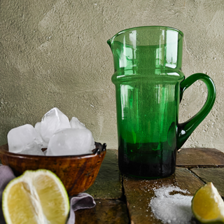 Green Beldi glass jug, tamegroute bowl with ice, lemons, and sugar over a tamegroute countertop.