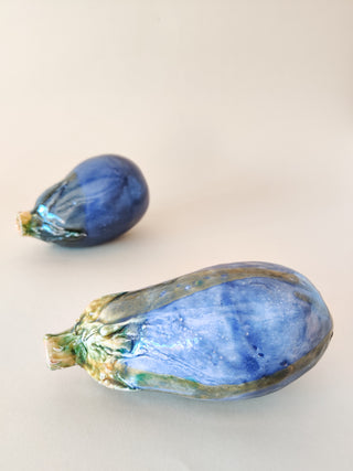  A vibrant cobalt blue and green ceramic eggplant, handcrafted in Spain. Its glossy finish reflects light, showcasing its uniqueness.