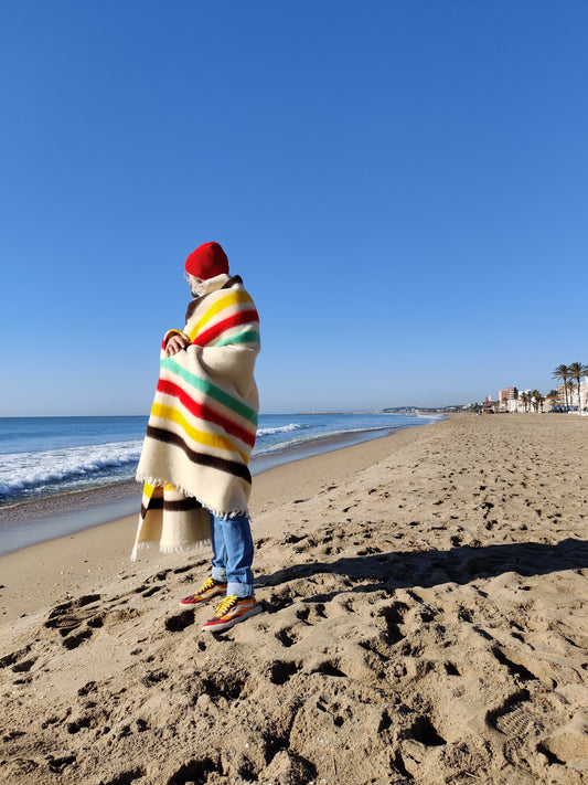 Man on a beach with a merino wool blanket similar to a hudson bay blanket.